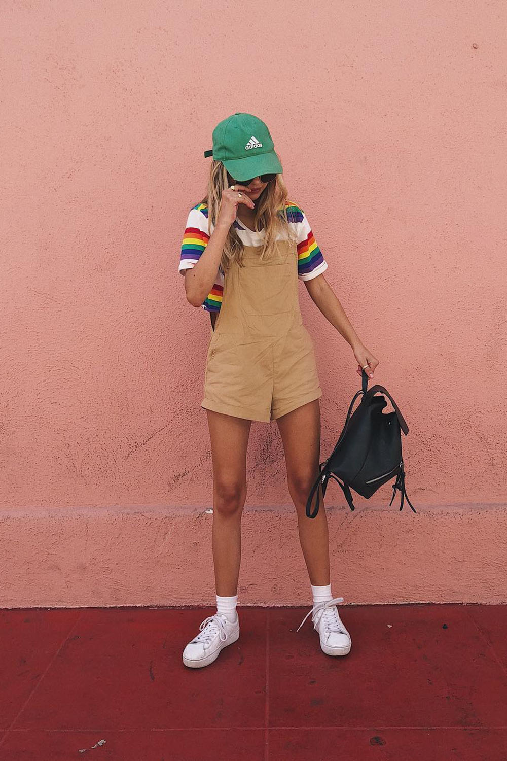 boné verde, jardineira bege, blusa listrada, tênis branco e mochilinha
