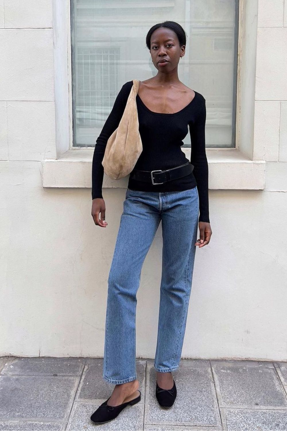Calça jeans reta, blusa preta de manga com cinto preto marcando, maxi bolsa e flat mule preto