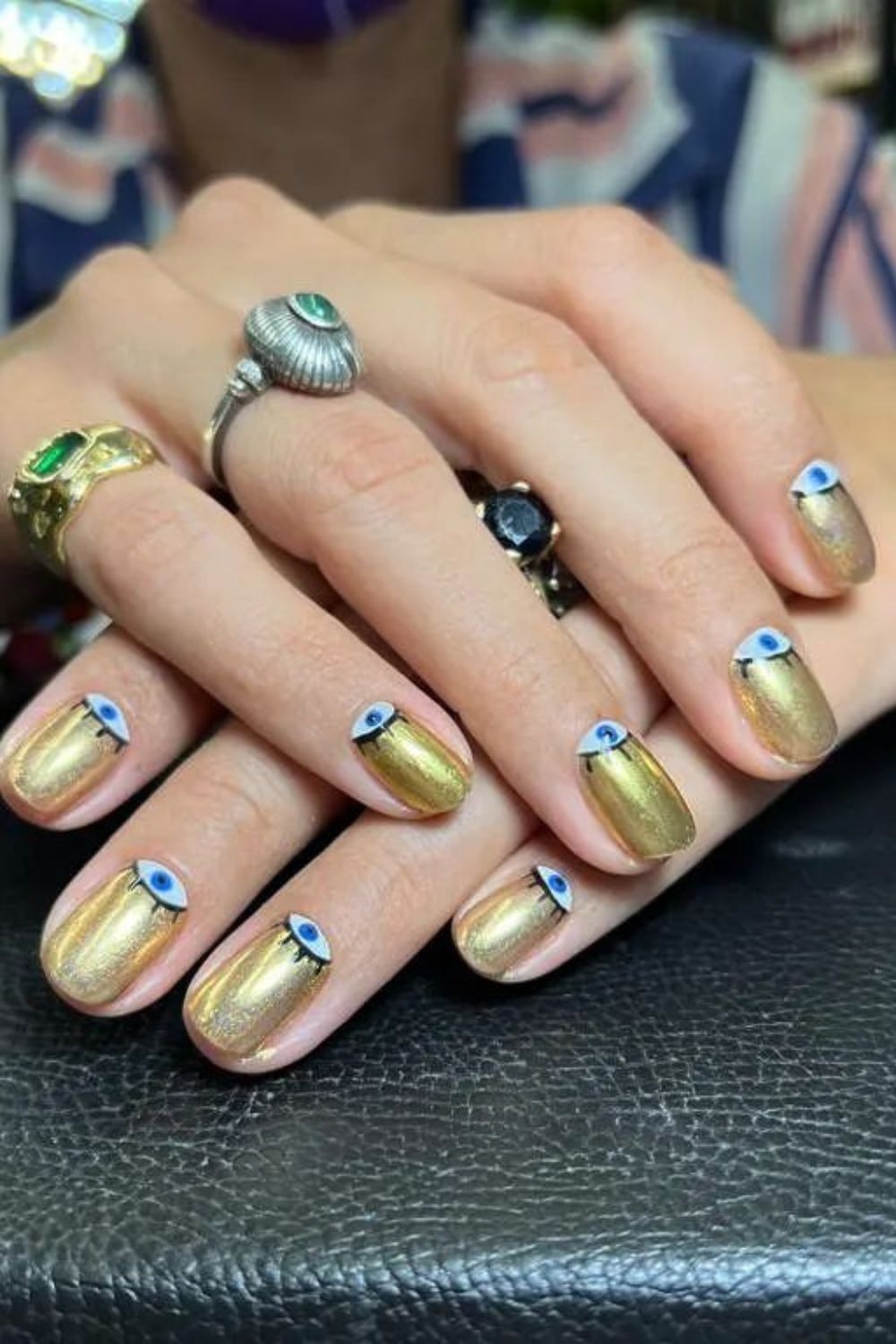 Unhas cintilantes douradas com nail art de olho grego