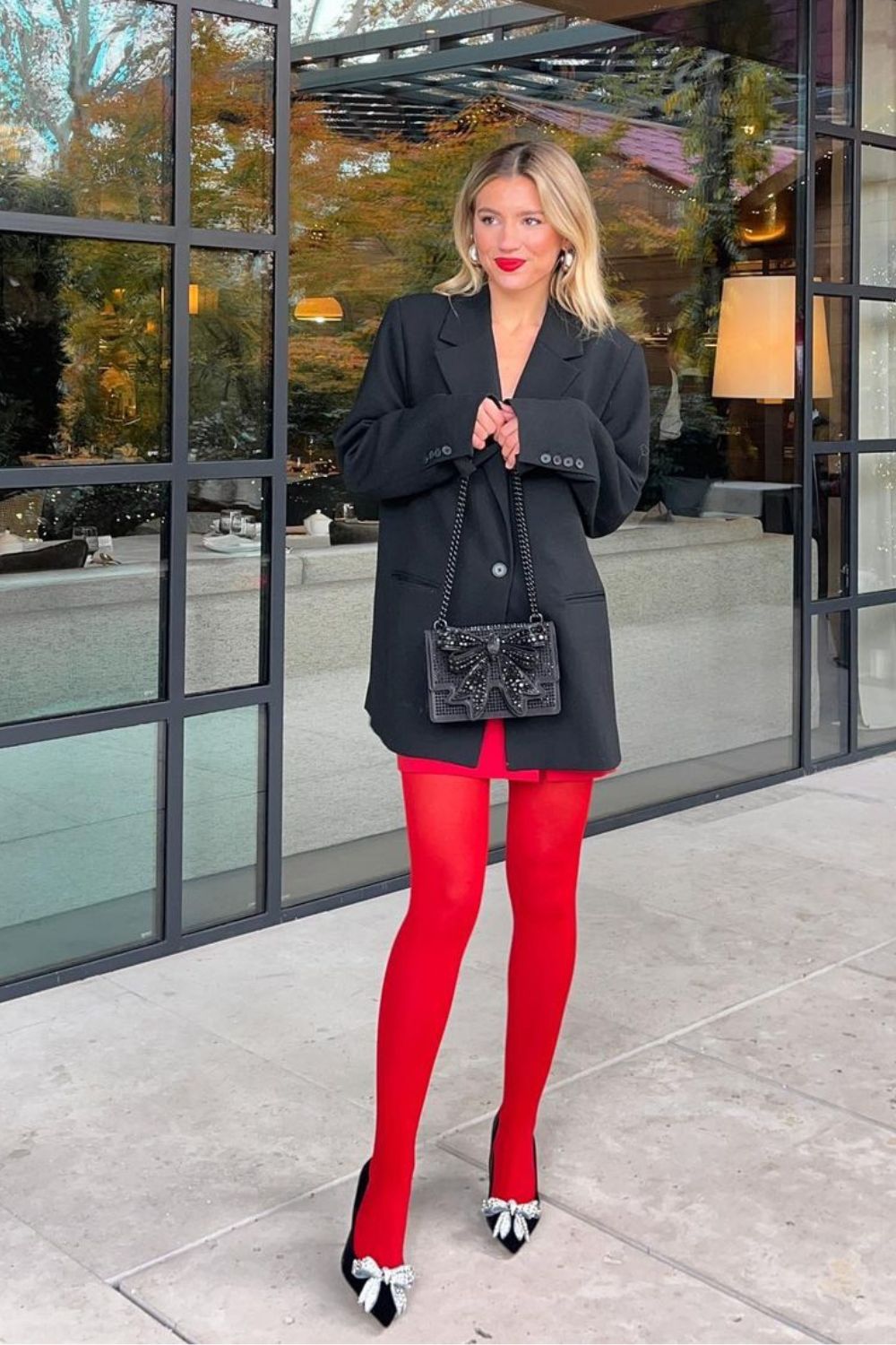 Blazer, minissaia e meia-calça vermelha com scarpin preto de lacinho
