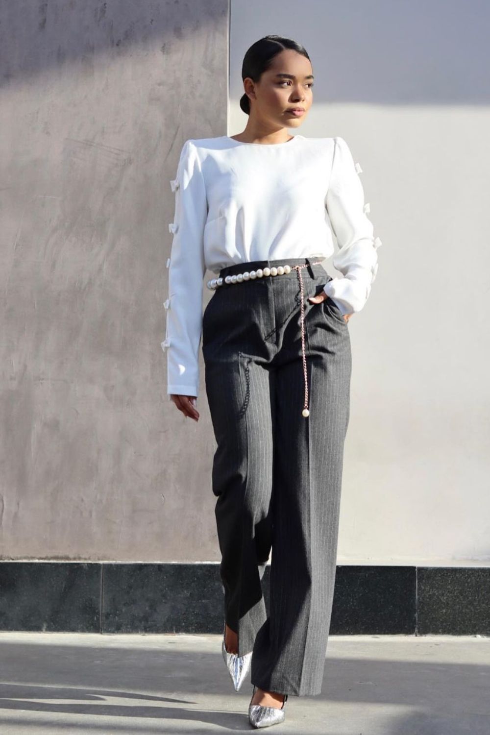 Blusa branca de manga, calça de alfaiataria cinza, cinto de corrente com pérolas e scarpin prata