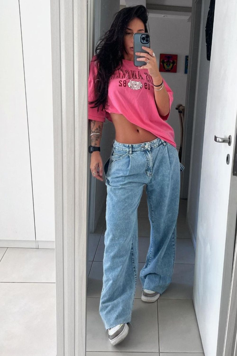 Blusa rosa, calça jeans de cintura baixa e tênis