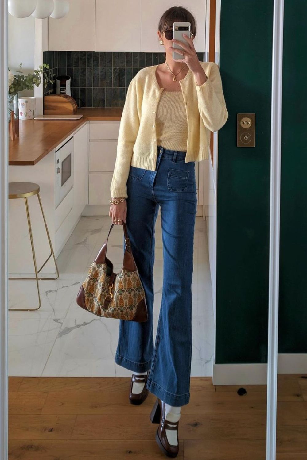 Estilo das francesas com Twin set amarelo com suéter e blusa de tricô, calça jeans flare, bolsa e mocassim vintage