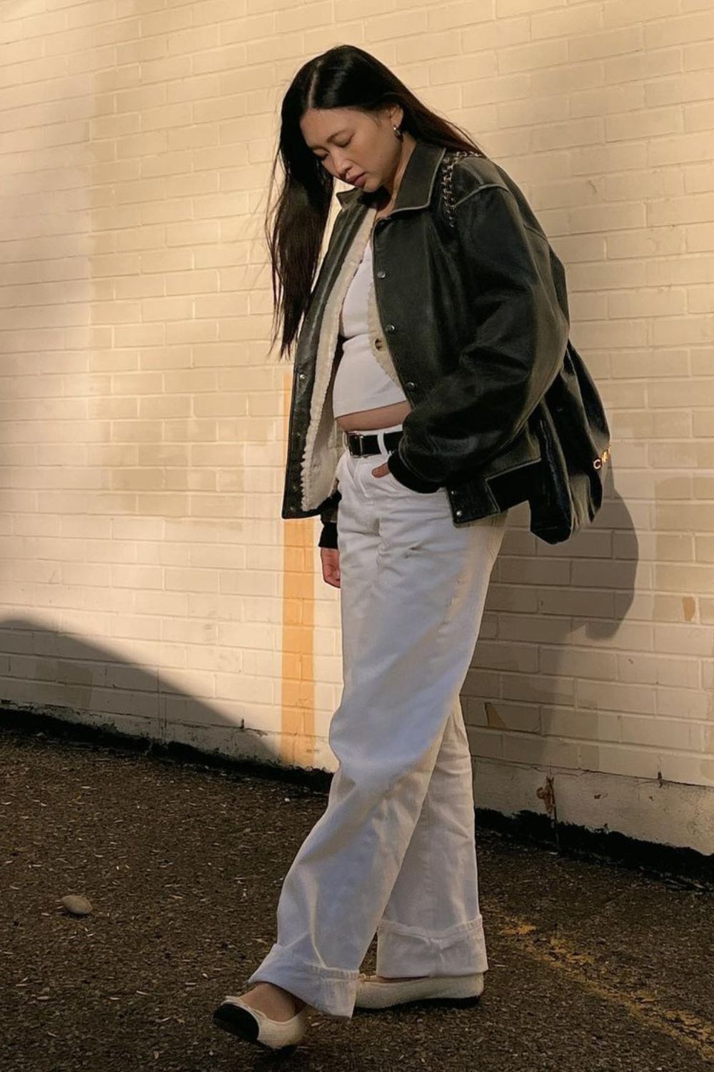 Blusa branca, jaqueta de couro oversized, calça jeans baggy e sapatilha bicolor