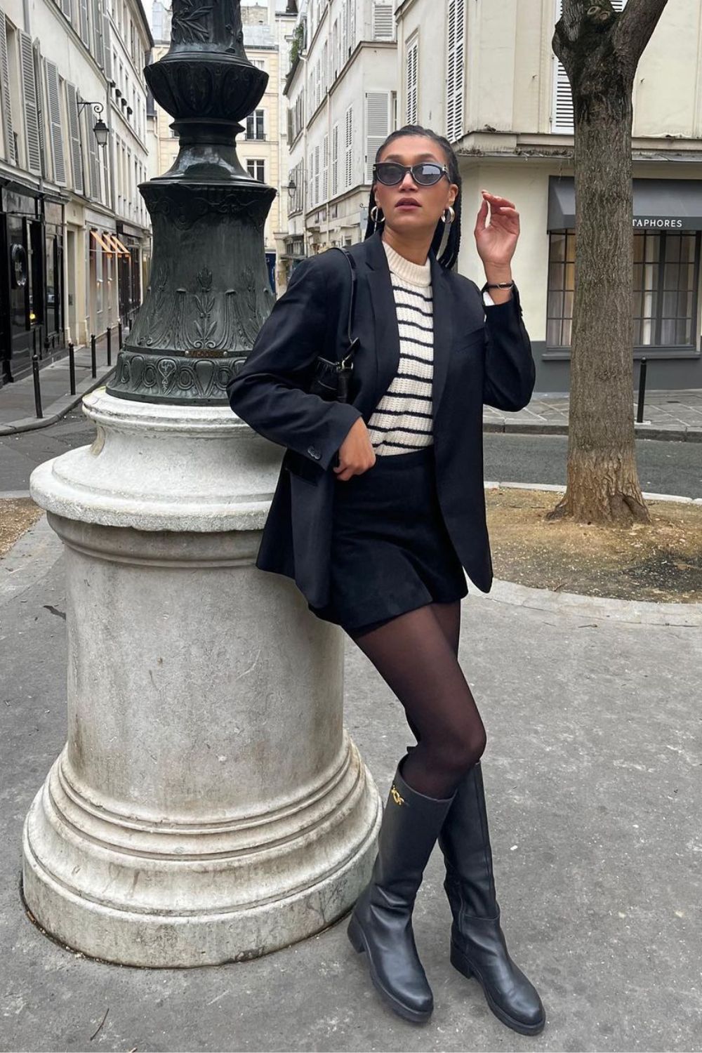 looks femininos, blazer preto, blusa listrada, short saia de alfaiataria, meia-calça e bota de cano alto