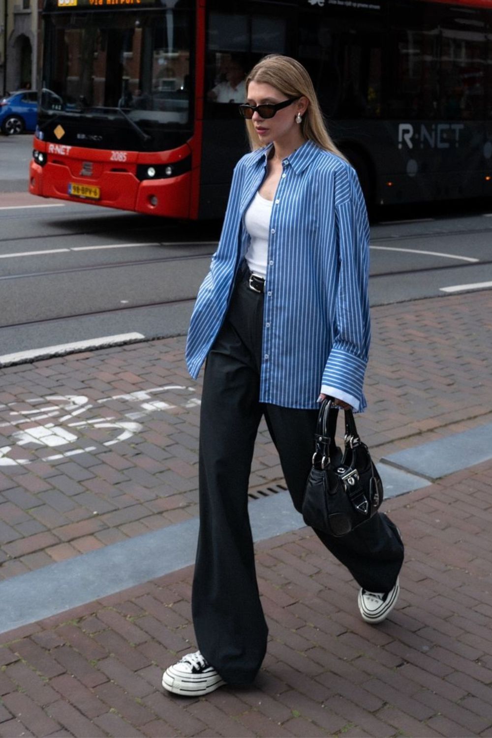 Camisa listrada coo terceira peça no look com regata branca, calça de alfaiataria preta e tênis plataforma