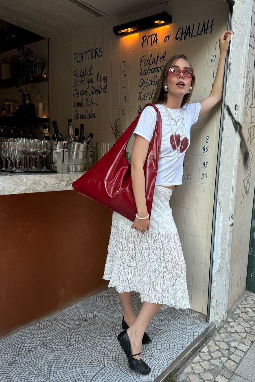 Bolsa vermelha, t-shirt de cereja, saia midi de renda e sapatilha preta