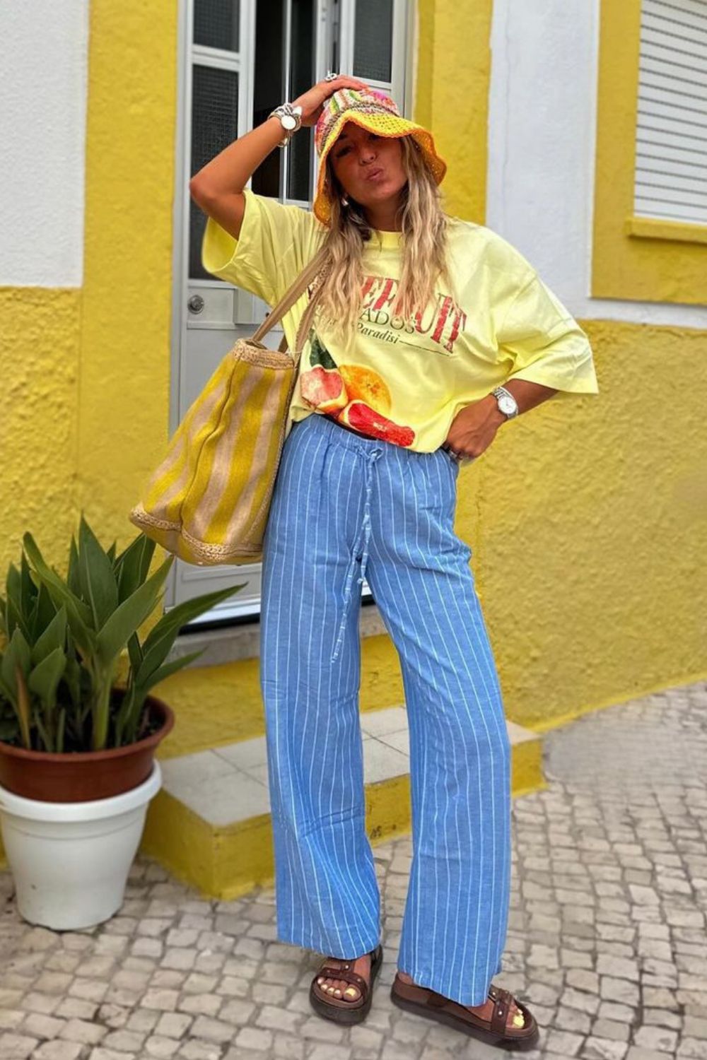 T-shirt tropical amarelo manteiga, bucket hat, calça listrada e papete