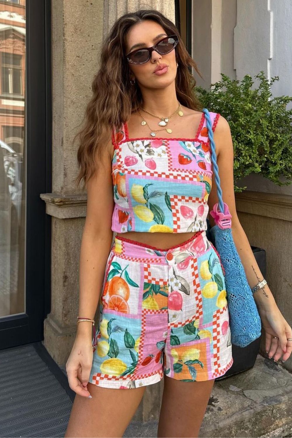 Looks para chamar atenção neste verão, conjuntinho com estampa tropical de frutas e bolsa azul