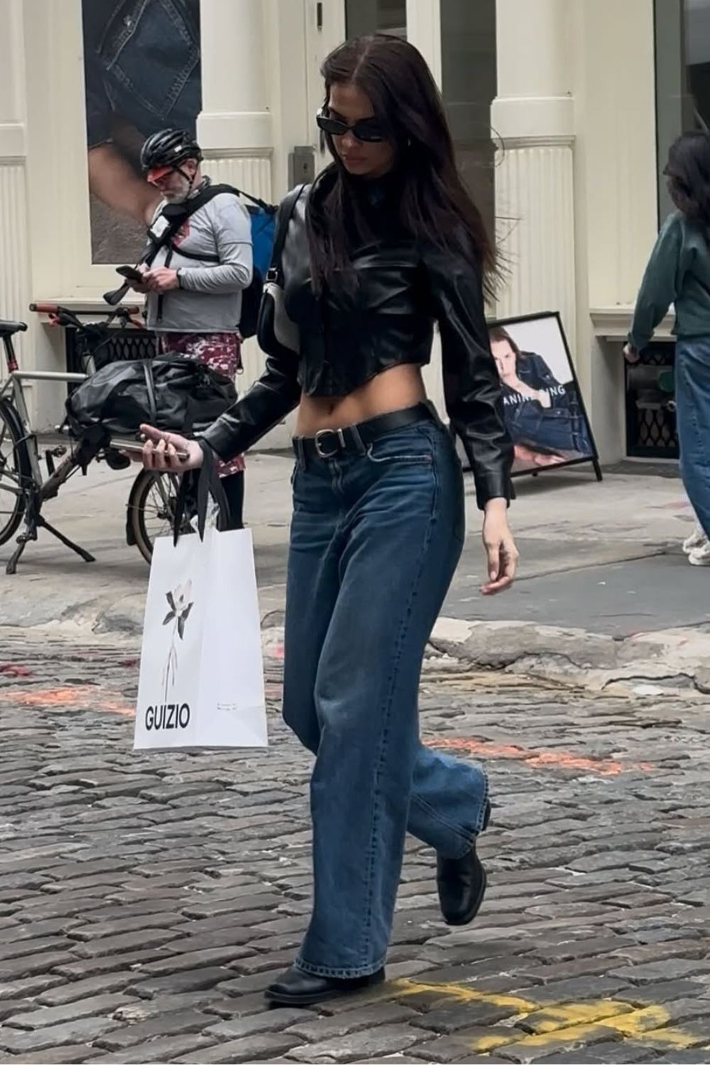 Jaqueta de couro cropped, calça jeans com cinto e bota preta