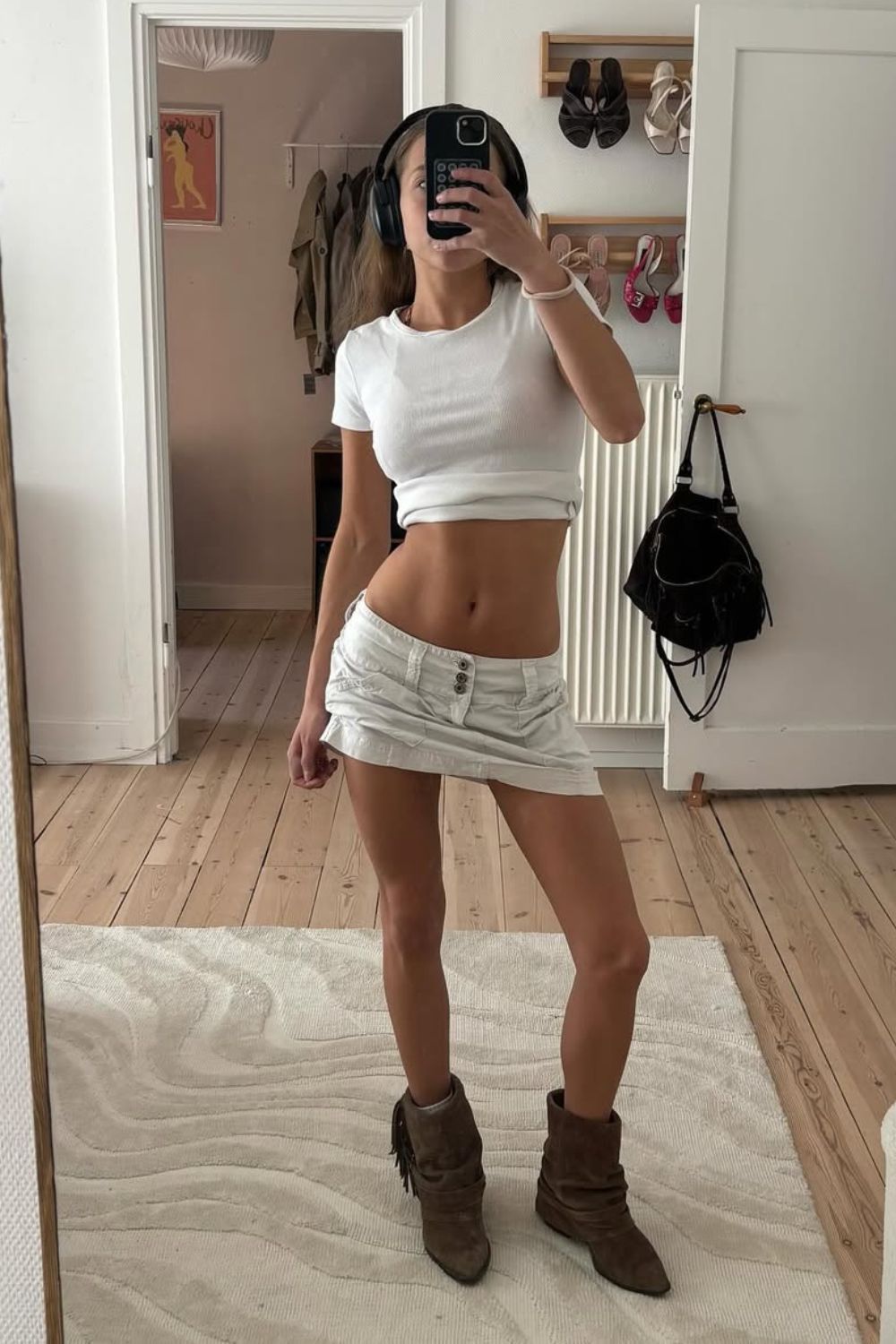 Cropped branco, minissaia de cintura super baixa e bota western