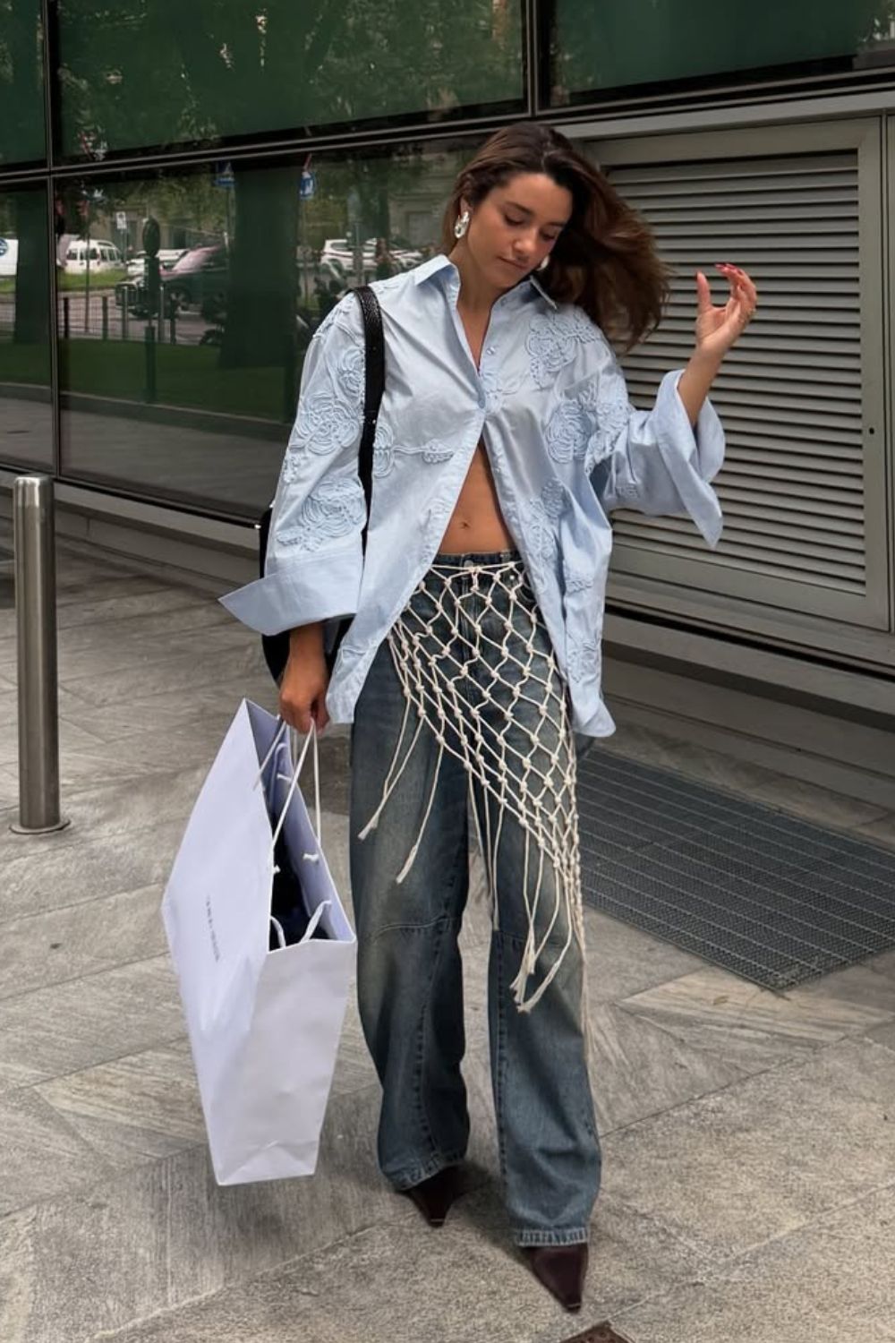 Camisa social com botões abertos, calça jeans com sobreposição de lenço artesanal
