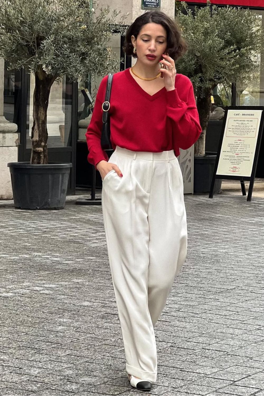 Suéter vermelho em gola v, bolsa baguete preta e calça de alfaiataria branca