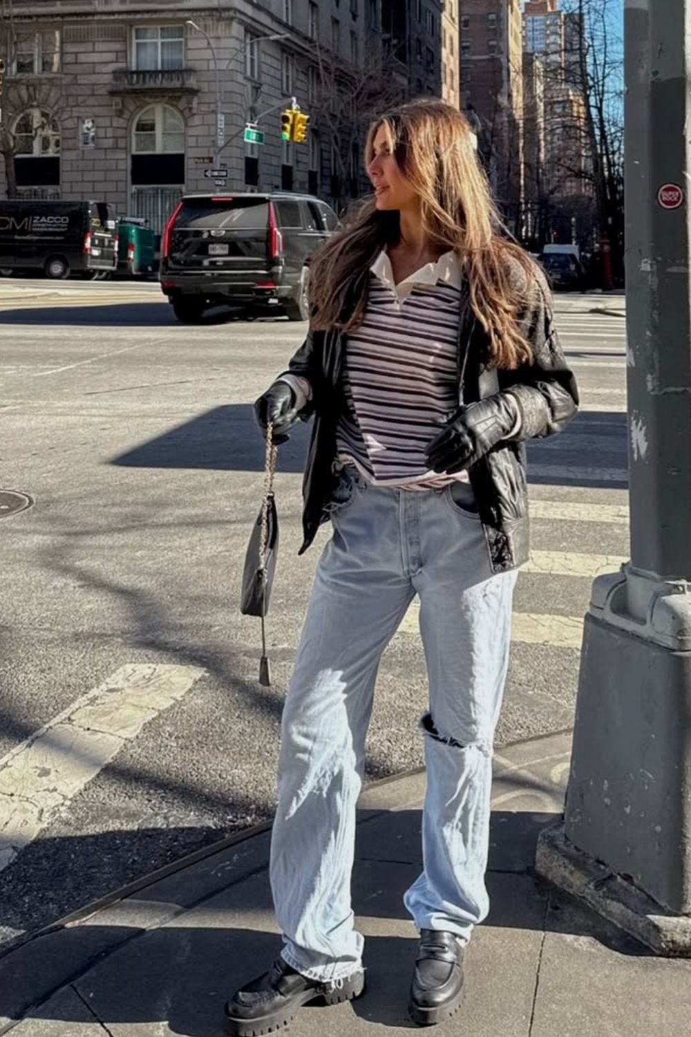 Calça jeans rasgada, blusa gola polo, jaqueta de couro, luvas e coturno