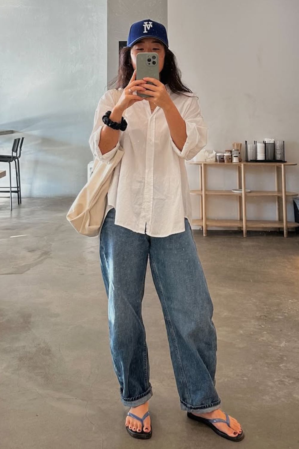 Look casual com camisa branca, boné, jeans baggy e rasteirinha