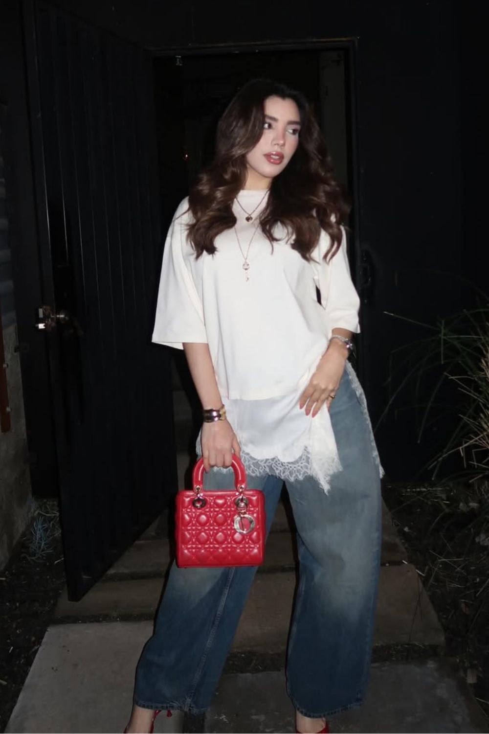 Sobreposição com blusa de renda e t-shirt branca, calça jeans wide leg e bolsa vermelha