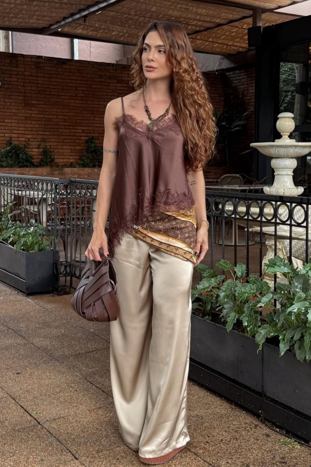 blusa de renda marrom. lenço no quadril e calça de cetim