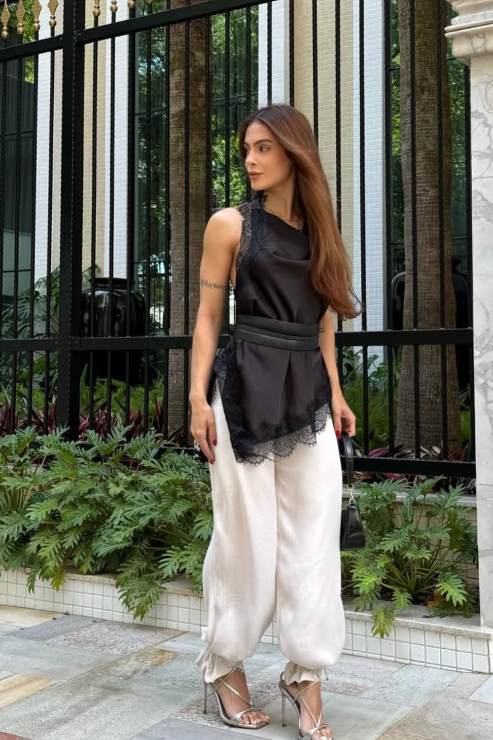 blusa de renda drapeada preta, calça balão e sandália dourada