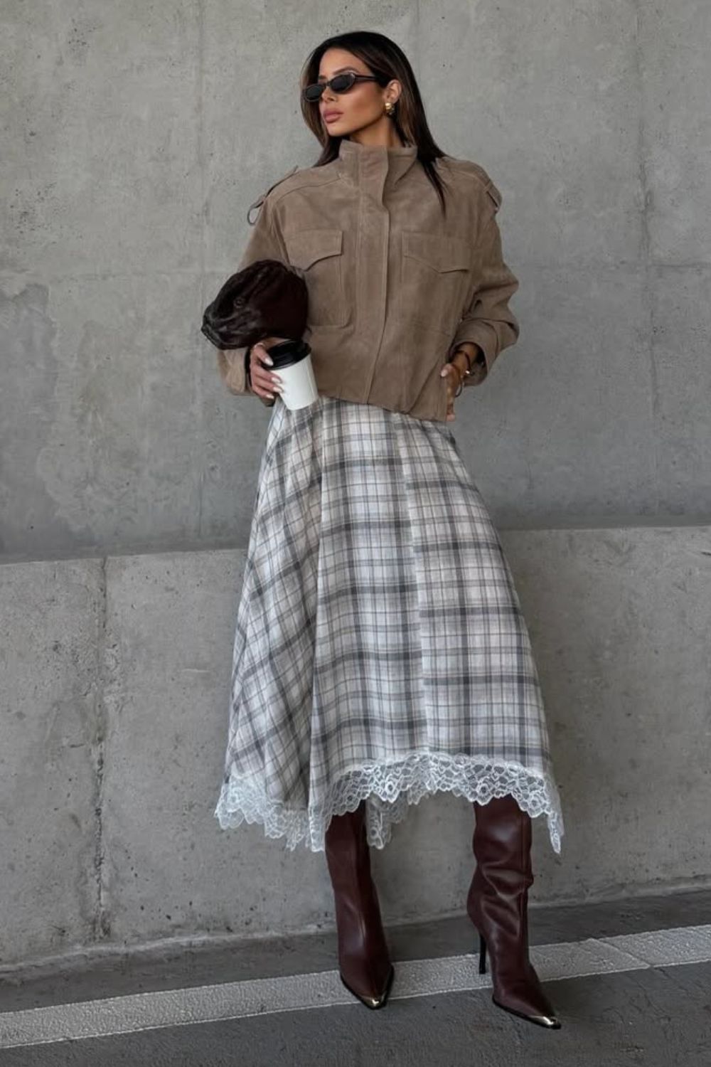 Bomber jacket cinza com saia midi xadrez e bota de cano alto