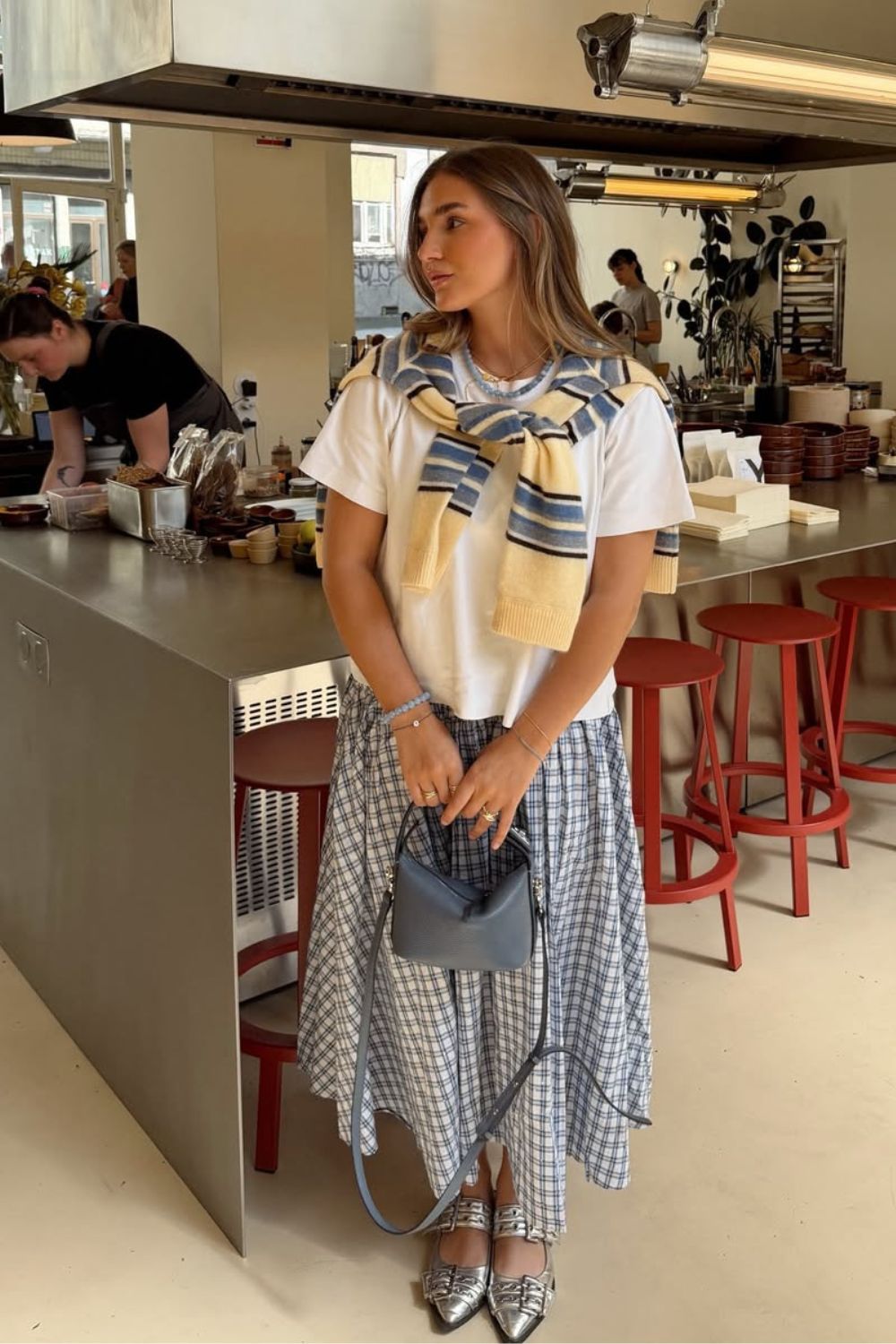 Blusa branca, suéter jogadinho sobre os ombros, saia godê xadrez e sapatilha prata