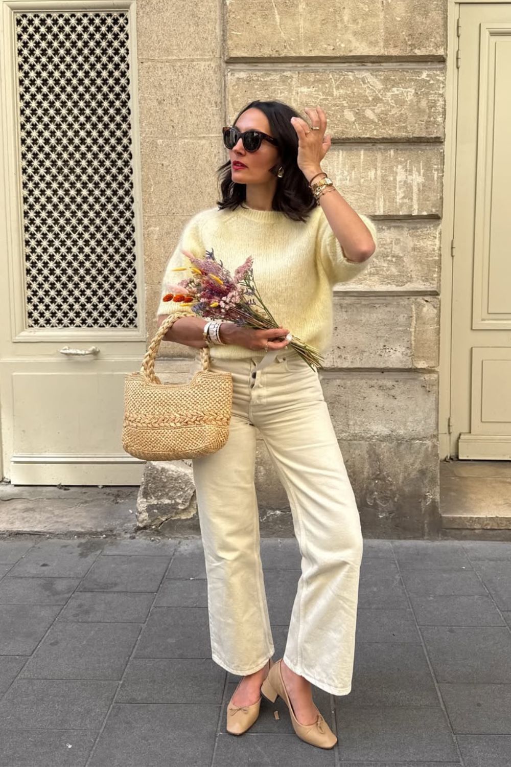Suéter de pelinho amarelo manteiga, calça caqui, bolsa de palha e sapatilha bege