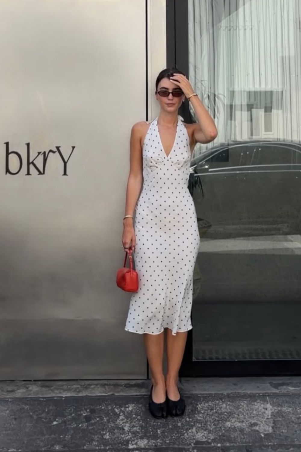 Looks românticos com vestido midi de poá com sapatilha pata e mini bolsa vermelha
